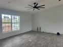 Spacious living room with wood-look tile flooring, large windows, and a ceiling fan at 13541 Jeronimo Ln, Port Charlotte, FL 33981