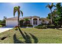 Charming home with a manicured front lawn, mature palm trees, and a well-maintained exterior at 15600 Aldama Cir, Port Charlotte, FL 33981