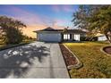 Inviting home exterior at sunset, featuring a large driveway and manicured lawn at 9509 St Paul Dr, Port Charlotte, FL 33981