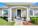 House entrance with a covered porch, dark door, and potted plants at 1858 Capitol St, North Port, FL 34288