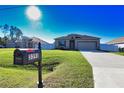 Charming home featuring a mailbox, expansive lawn, concrete driveway, and stone accents near the entryway at 3393 Kacher Rd, North Port, FL 34288