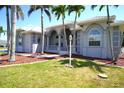 Charming single-story home featuring an arched entryway, well-manicured lawn, and lush palm trees at 649 Maltese Dr, Punta Gorda, FL 33950