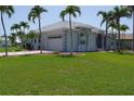 Well-maintained home with a two-car garage, lush green lawn and a lovely walkway and palm trees at 649 Maltese Dr, Punta Gorda, FL 33950