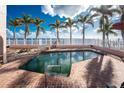 Backyard pool featuring a brick patio, palm trees, and views of the bay at 341 Severin Se Rd, Port Charlotte, FL 33952