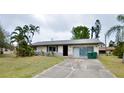 Front exterior of a single-story home with a driveway, landscaping, and palm trees at 11332 8Th Ave, Punta Gorda, FL 33955