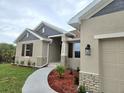 Tan stucco home with gray accents, brown shutters, stone accents, and manicured landscaping at 13480 Allentown Ave, Port Charlotte, FL 33981