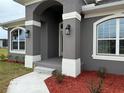 Beautiful entryway features an arched front porch, decorative lighting, and tidy landscaping at 233 W Pine Valley Ln, Rotonda West, FL 33947
