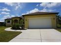 Front exterior shot of a well-maintained yellow house with a two-car garage and a long driveway at 25115 Esmeralda Ct, Punta Gorda, FL 33955