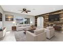 Bright living room with a ceiling fan, large windows and rustic wood accent wall at 1190 Victoria Ave Nw, Port Charlotte, FL 33948