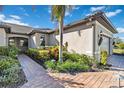 Brick-paved walkway leading to a light beige house with lush landscaping at 12750 Oriago St, Venice, FL 34293