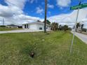Side view of a house with a two-car garage and a green lawn at 200 Dolphin Pkwy, Punta Gorda, FL 33950