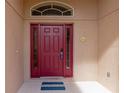 Red front door entry with sidelights and a decorative doormat at 2507 Hobblebrush Dr, North Port, FL 34289