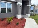 Inviting front entrance with gray columns, manicured shrubs, and a paved walkway at 9159 Melody Cir, Port Charlotte, FL 33981
