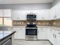 Modern kitchen features white cabinets, stainless steel appliances, neutral countertops, and a stylish backsplash at 1796 Scarlett Ave, North Port, FL 34289