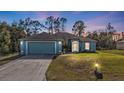 Evening view of a charming blue home with illuminated landscaping and driveway at 18359 Gypsy Ave, Port Charlotte, FL 33954