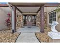 Inviting front entryway featuring a decorative stone facade, covered porch, and well-maintained landscaping at 23309 Hartley Ave, Port Charlotte, FL 33954