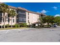 View of the condo building with lush landscaping and parking area at 25188 Marion Ave # A108, Punta Gorda, FL 33950