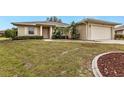 One-story home with a large front lawn, landscaping, and an attached garage at 26090 Huanuco Dr, Punta Gorda, FL 33983