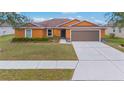 One-story home with orange exterior, two-car garage, and landscaped front yard at 7314 61St E St, Palmetto, FL 34221