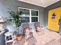 Inviting front porch with yellow door, two chairs, and potted plant at 27240 Tribune Blvd, Punta Gorda, FL 33955