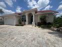 Beautiful home showcasing a terracotta roof, arched entryway, and a paver driveway at 3730 Whippoorwill Blvd, Punta Gorda, FL 33950