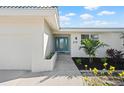 Inviting front exterior featuring a turquoise door, manicured landscaping, and a white exterior at 210 Divinci Dr, Punta Gorda, FL 33950