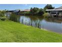 A view of the waterfront backyard with lush green grass extending to the canal and boat lifts at 9506 Melody Cir, Port Charlotte, FL 33981