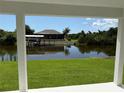 Waterfront view framed by patio posts showing a private dock, serene water, and beautiful landscaping at 9506 Melody Cir, Port Charlotte, FL 33981