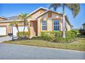 Tan villa with two-car garage, landscaping, and palm trees at 1916 Nottingham Trl, Punta Gorda, FL 33980