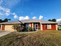 Red house with gray roof, attached garage, and landscaped lawn at 23104 Rountree Ave, Port Charlotte, FL 33980