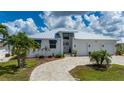 Inviting single-story home with a metal roof, three-car garage, brick-paved driveway, and beautifully landscaped yard at 2750 W Marion Ave, Punta Gorda, FL 33950