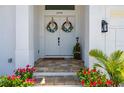 Elegant double front doors with floral wreaths, set off by red flowers and a stone tile entryway at 2750 W Marion Ave, Punta Gorda, FL 33950