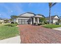 Brick paver driveway leading to a one-story home with a screened-in garage at 15292 Mille Fiore Blvd, Port Charlotte, FL 33953