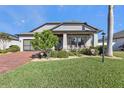 Curb appeal of the home with landscaping, brick driveway, and porch at 15292 Mille Fiore Blvd, Port Charlotte, FL 33953