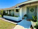 Inviting covered porch with lush greenery and a stylish front door with decorative wreath at 3202 Meadow Run Dr, Venice, FL 34293