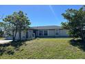 Charming single-story home featuring a well-maintained lawn, mature trees, and a light gray exterior at 12143 Du Barry Ave, Port Charlotte, FL 33981