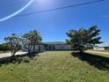 Charming single-story home with a well-maintained lawn and mature trees under a clear blue sky at 12143 Du Barry Ave, Port Charlotte, FL 33981