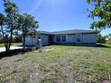 Charming single-story home with a well-maintained lawn and lush trees on a sunny day at 12143 Du Barry Ave, Port Charlotte, FL 33981