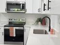 Bright kitchen features stainless steel appliances, white cabinets, black hardware, and white countertops at 1100 Belkton Ave, Port Charlotte, FL 33948