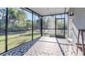 The screened-in porch has an outdoor rug covering the floor with views of the green backyard at 2784 Dode Ave, North Port, FL 34288