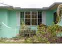 Home exterior with a large bay window framed by white shutters, complemented by lush green foliage and plants at 1845 Edison Dr, Englewood, FL 34224