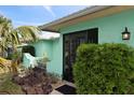 Inviting turquoise home featuring lush landscaping, a black-framed entryway and decorative exterior lighting fixture at 1845 Edison Dr, Englewood, FL 34224