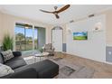 Bright living room features a ceiling fan, mounted tv, tiled floors, and a sliding glass door to a balcony at 14091 Heritage Landing Blvd # 121, Punta Gorda, FL 33955