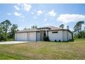 A modern home featuring a two-car garage, manicured lawn, and a minimalist landscape design at 5435 Montego Ln, Port Charlotte, FL 33981