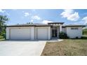 A front exterior of a modern home with a white facade, two-car garage, and meticulously kept lawn at 5435 Montego Ln, Port Charlotte, FL 33981