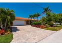 Charming home featuring a red tile roof, lush landscaping, and a brick driveway, exuding curb appeal and inviting warmth at 805 Brenda Ct, Punta Gorda, FL 33950