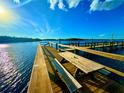 Scenic view of a wooden dock with a picnic table extending into the tranquil waters under a clear blue sky at 500 Woodstork Ln, Punta Gorda, FL 33982