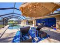 Inviting screened pool area with brick pavers, lounge chairs, and umbrella at 18395 Edgewater Dr, Port Charlotte, FL 33948
