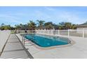 Community pool with a white fence, tables and a backdrop of lush trees in this appealing backyard at 24540 Harborview Rd # E4, Port Charlotte, FL 33980