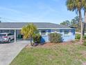 Charming light-blue home with manicured lawn, white trim and a modern vehicle parked in the carport at 1956 Wyoming Ave, Englewood, FL 34224